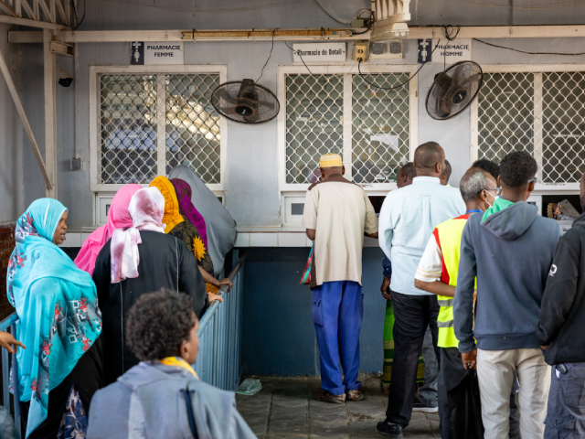 Two lines of people queuing at a rural African pharmacy
